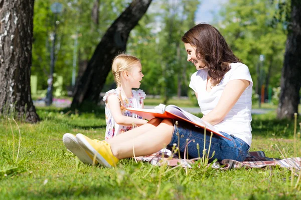 Chica y una mujer joven leyendo un libro — Foto de Stock