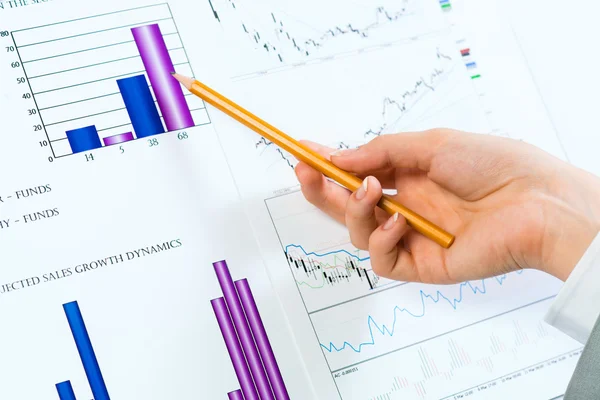 Female hand on financial charts — Stock Photo, Image