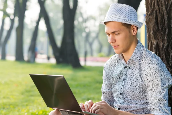 带着笔记本电脑在公园里工作的年轻人 — 图库照片