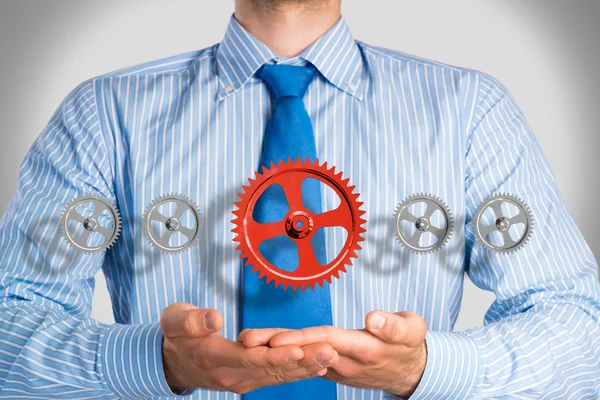 Affärsman håller upp en mekanism av kugghjul — Stockfoto