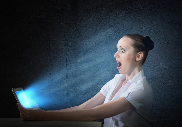 Woman holding a tablet in a dark room — Stock Photo, Image