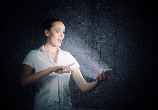 Mujer sosteniendo un teléfono celular en una habitación oscura — Foto de Stock