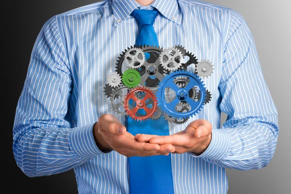 Business man holds up a mechanism of gears — Stock Photo, Image