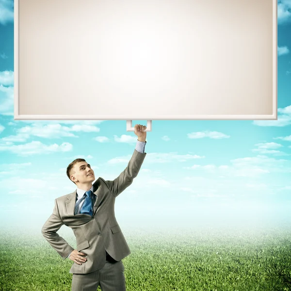 Businessman holding a banner with one hand — Stock Photo, Image