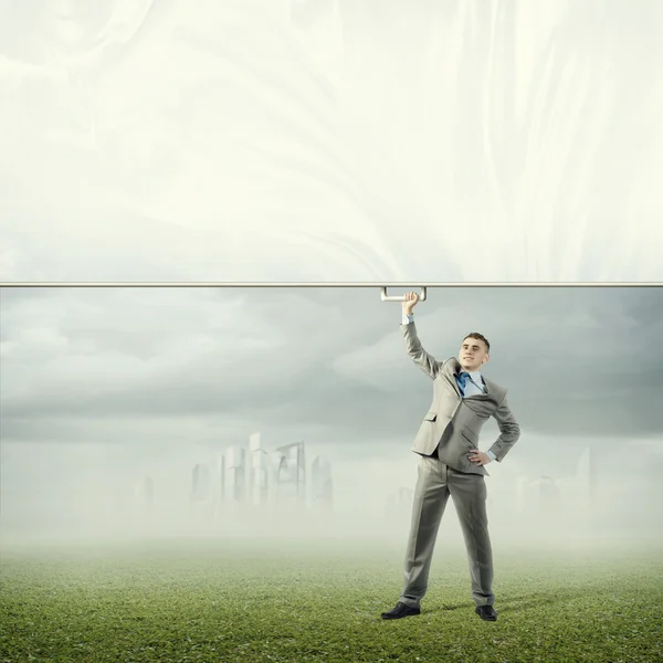 Businessman holding a banner with one hand — Stock Photo, Image