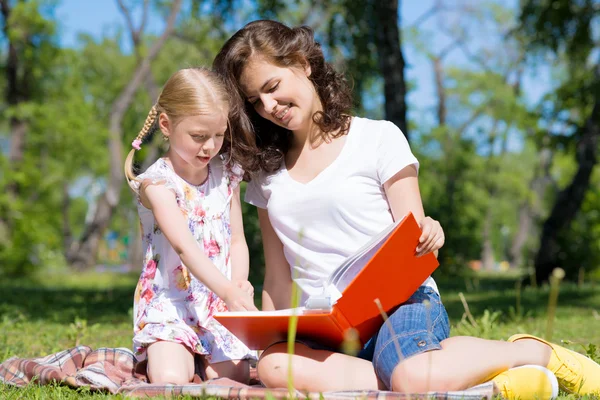 Girl and a young woman reading a book together — Stock Photo, Image