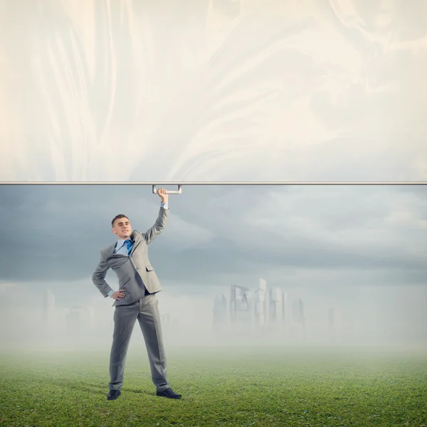 Businessman holding a banner with one hand — Stock Photo, Image