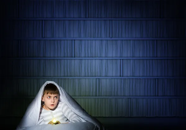 Boy under the covers with a flashlight — Stock Photo, Image