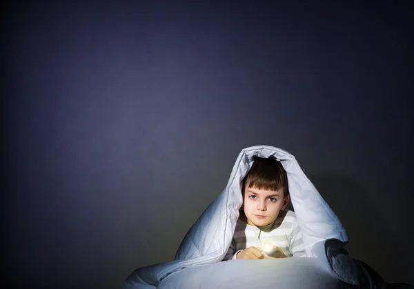 Junge mit Taschenlampe unter der Decke — Stockfoto
