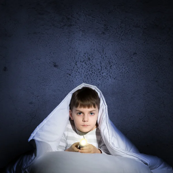 Boy under the covers with a flashlight — Stock Photo, Image