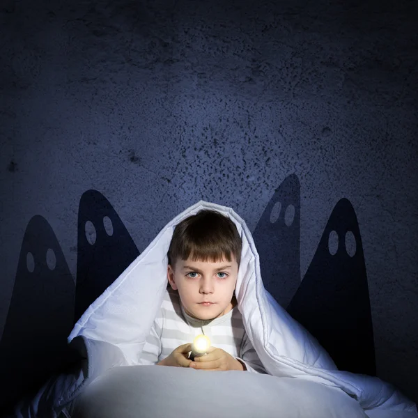 Niño bajo las sábanas con una linterna — Foto de Stock