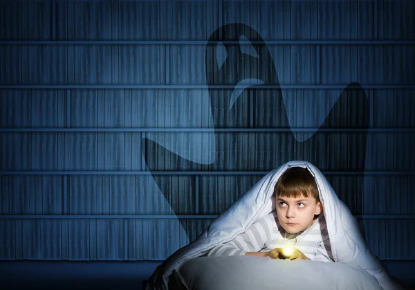 Bir el feneri ile yorganın altında çocuk — Stok fotoğraf