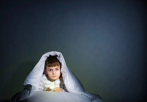 Junge mit Taschenlampe unter der Decke — Stockfoto