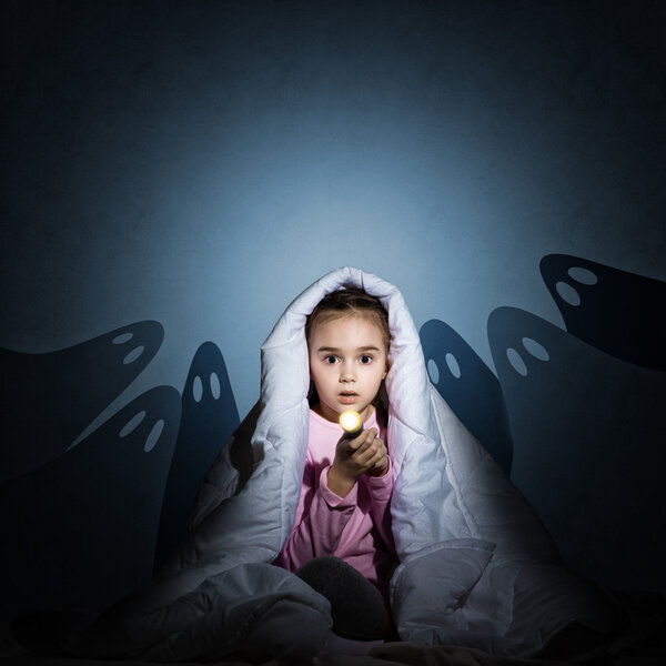 girl under the covers with a flashlight