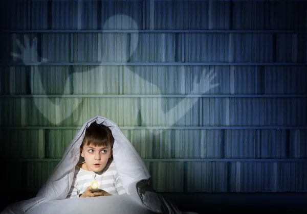 Boy under the covers with a flashlight — Stock Photo, Image