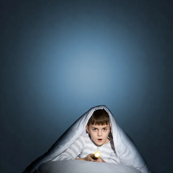 Boy under the covers with a flashlight — Stock Photo, Image