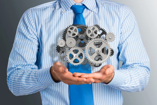 Business man holds up a mechanism of gears — Stock Photo, Image