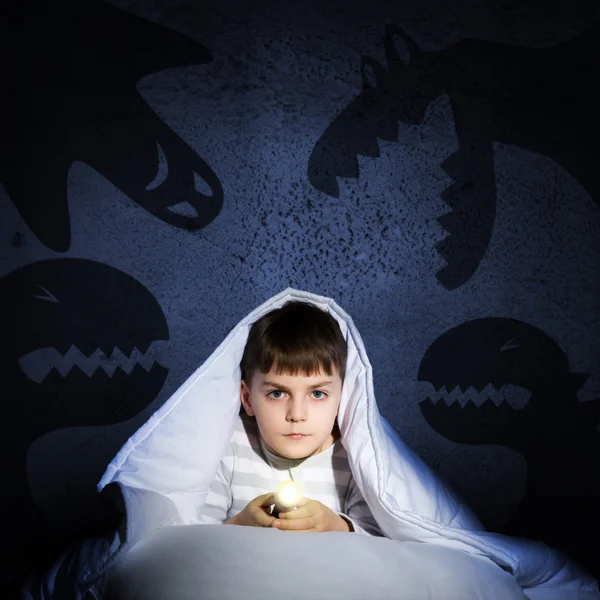 Boy under the covers with a flashlight — Stock Photo, Image