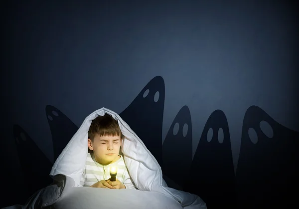 Boy under the covers with a flashlight — Stock Photo, Image