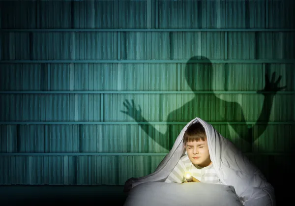 Boy under the covers with a flashlight — Stock Photo, Image