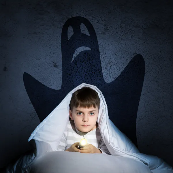 Boy under the covers with a flashlight — Stock Photo, Image