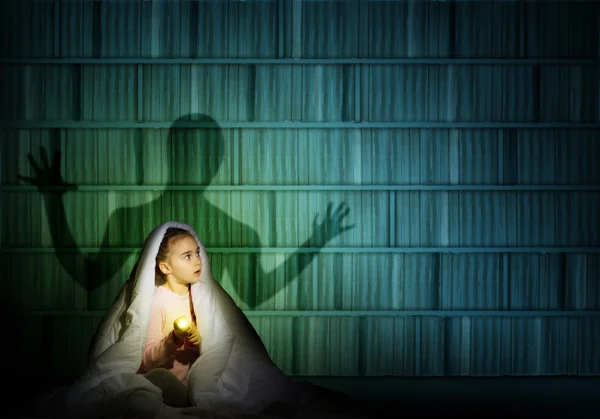 Girl under the covers with a flashlight — Stock Photo, Image