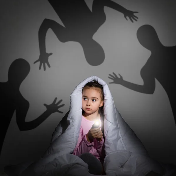 Girl under the covers with a flashlight — Stock Photo, Image