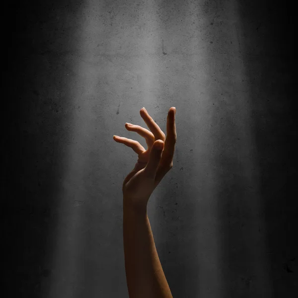 A mão da mulher alcança os raios de luz — Fotografia de Stock