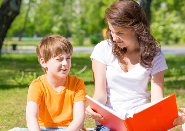 Niño y una mujer leyendo un libro juntos — Foto de Stock