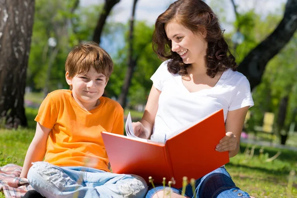 Boy and a woman reading a book together — Stock Photo, Image