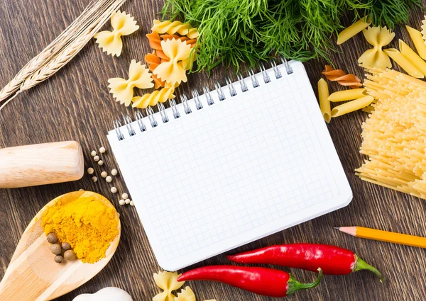 Spices, pasta and vegetables around notebook — Zdjęcie stockowe
