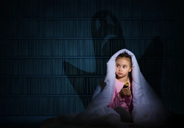 Girl under the covers with a flashlight — Stock Photo, Image