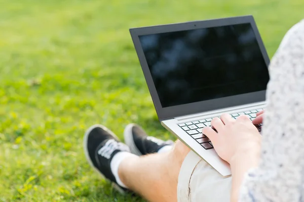 Joven que trabaja en el parque con un ordenador portátil —  Fotos de Stock