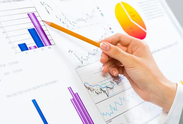 Mão feminina apontando lápis em gráficos financeiros — Fotografia de Stock