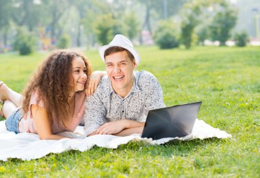 Çift birlikte parkta laptop ile yalan
