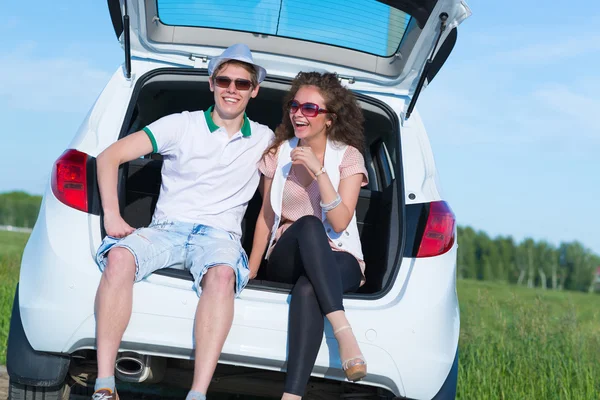 Unga paret sitter i öppna bagageluckan — Stockfoto