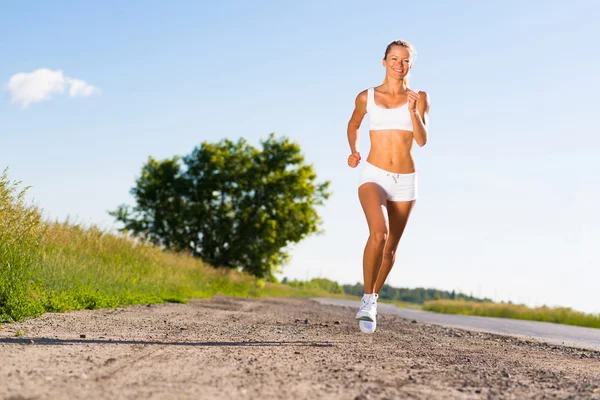 Mujer atlética joven corriendo en el camino — Foto de Stock