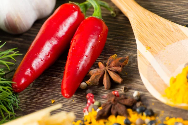 Chili, Kräuter und Gewürze liegen auf einer Holzoberfläche — Stockfoto