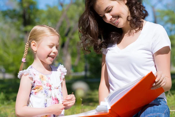 Girl and a young woman reading a book together — Stock Photo, Image