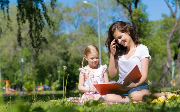 Chica y una mujer joven leyendo un libro juntos —  Fotos de Stock