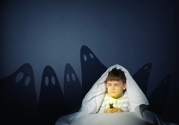 Boy under the covers with a flashlight — Stock Photo, Image