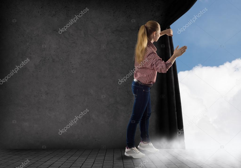 young woman pushes the curtain looking at clouds