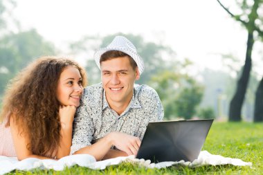 Çift birlikte parkta laptop ile yalan