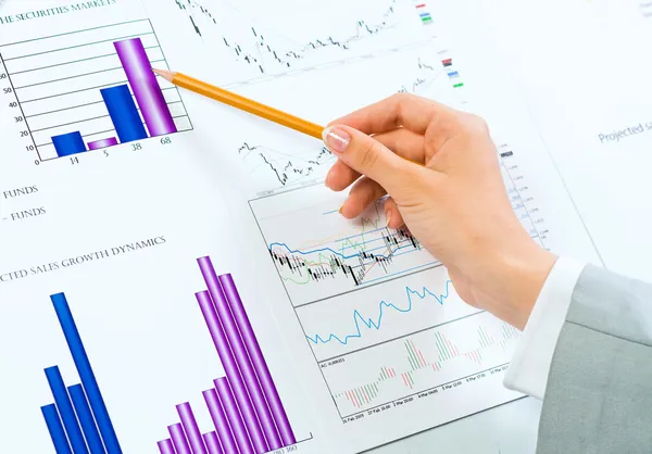 Female hand pointing pencil on financial charts — Stock Photo, Image