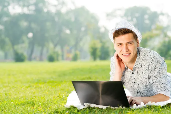 Parkta dizüstü bilgisayarla çalışan genç bir adam. — Stok fotoğraf