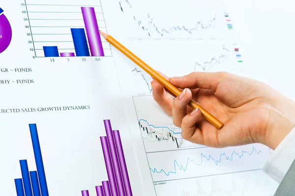 Female hand pointing pencil on financial charts — Stock Photo, Image