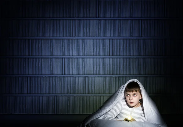 Мальчик под одеялом с фонариком — стоковое фото