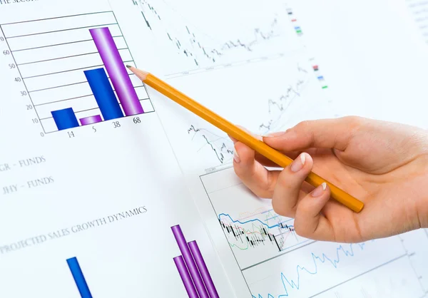 Female hand pointing pencil on financial charts — Stock Photo, Image