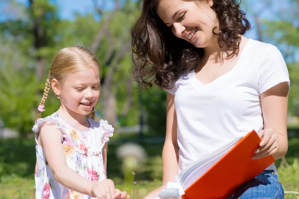 Girl and a young woman reading a book together — Stock Photo, Image