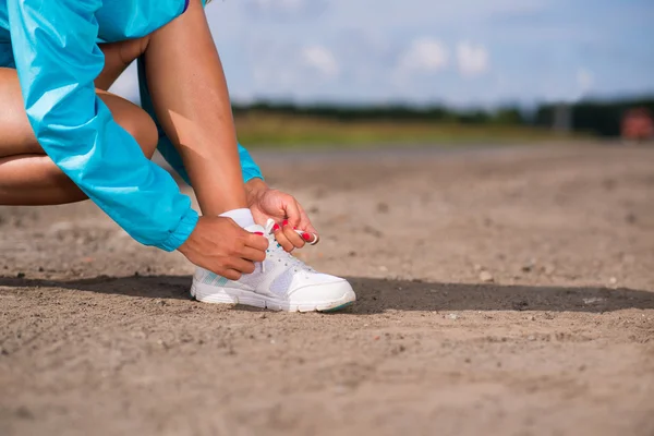 Wanita muda mengikat tali sepatu pada sepatu olahraga — Stok Foto